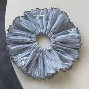 Detail of grey-blue pleated scrunchie with white ribbon bows and elegant pearls