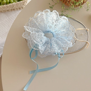 Détail d'un chouchou en dentelle bleu clair avec rubans sur un plateau en argent chic