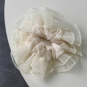 Close-up of beige lace scrunchie showing detailed satin fabric and mesh pleated edges