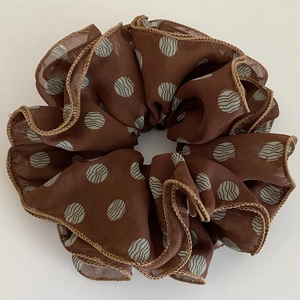 Detail of brown polka dot organza scrunchie with blue wavy patterns and edge stitching