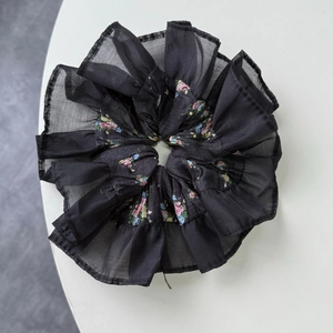 Détail du chouchou noir à fleurs avec volants en dentelle et motifs floraux colorés