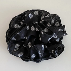 Detailed view of the sheer black polka dot scrunchie with fine stitching and soft fabric folds