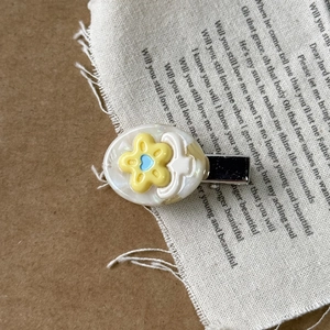 Detail of sweet floral acetate hair clip with yellow flower on a white oval base