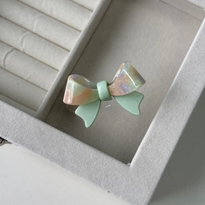 Close-up of a pastel marbled acetate bow hair clip on a soft velvet jewelry box