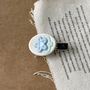 Macro detail of a Korean style acetate floral hair clip on a vintage fabric background