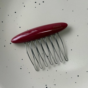 Detail of red acetate hair comb with ten silver metal teeth and gold handmade lettering