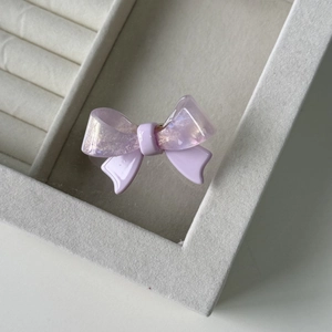 Detailed close-up of a purple acetate bow hair clip showing iridescent and matte textures