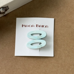 Détail de deux barrettes ovales en acétate bleu clair à texture marbrée sur carte