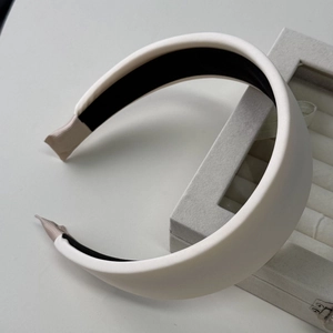 Close-up of white padded satin headband with non-slip lining and protective end caps