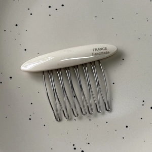 Detailed macro view of acetate hair comb featuring ten wavy metal teeth and gold label