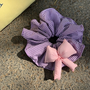 Detail of blue plaid fabric hair tie with pink plush bow in Korean balletcore style