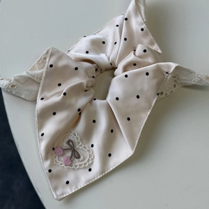 Détail d'un chouchou en satin beige à pois noirs avec broderie cœur et cerise rose