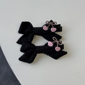 Détail de deux pinces à cheveux en tissu noir avec broderie florale rose au style sucré