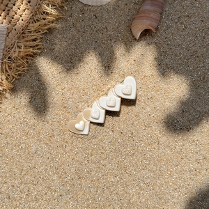 Summer vacation acetate hair clip with five cream heart shapes on a sandy beach background
