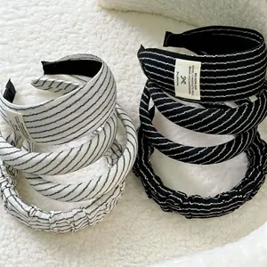 Close-up of black and white striped headband set with fabric label on soft texture