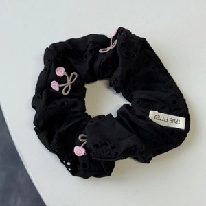 Vue détaillée du chouchou noir avec broderie florale évidée et motifs cerises roses