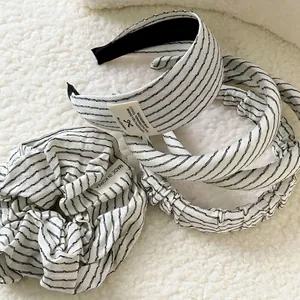 Minimalist black and white striped headband set with hair scrunchie on plush background