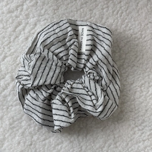Close-up of a striped scrunchie with a Made in Korea label on soft white texture