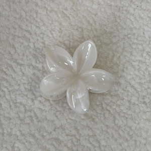 Gros plan sur une pince à cheveux fleur de frangipanier blanche sur tissu texturé