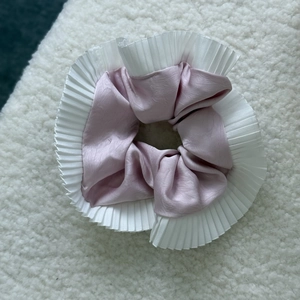 Detail of lavender satin scrunchie with white pleated chiffon lace on soft white texture