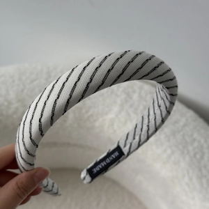 Detailed close-up of handmade white fabric headband with black stripes and label