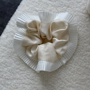 Detail of silk satin scrunchie with white pleated organza trim on soft texture