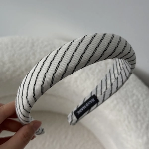 Macro shot of padded white headband with black stripes and handmade fabric label
