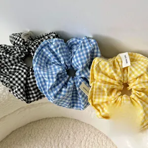 Detailed view of three handmade plaid scrunchies in black, blue, and yellow patterns