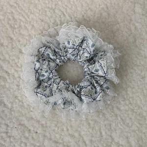 Close-up of floral hair scrunchie with light blue patterns and sheer lace trimming detail