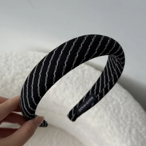 Detailed close-up of the black striped fabric headband with a woven Handmade label