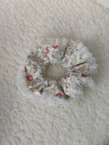 Detailed close-up of floral fabric hair scrunchie with delicate white lace trim