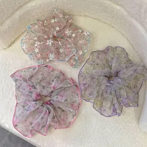 Chouchous en organza fleuri aux trois motifs pastel sur un fond texturé blanc
