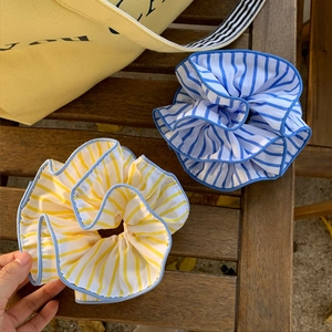 Yellow and blue striped fabric scrunchies set on a wooden table with a summer vibe