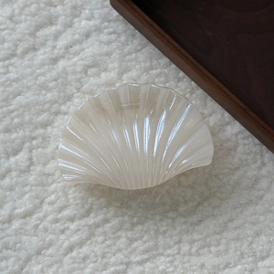 Détail de la pince à cheveux coquillage nacrée avec finition brillante sur tissu peluche
