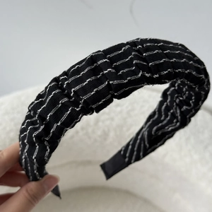 Detail showing pleated texture and white stripes on black fabric headband accessory