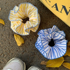 Two yellow and blue striped scrunchies displayed on ground for a casual outdoor hairstyle