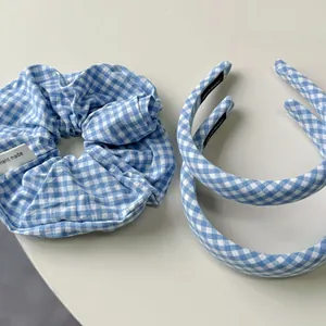 Detail of blue and white plaid padded headbands and scrunchie set on white surface