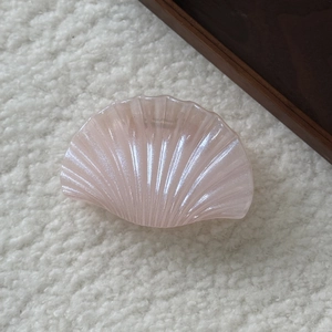 Gros plan détaillé d'une pince à cheveux coquillage rose nacré sur polaire douce