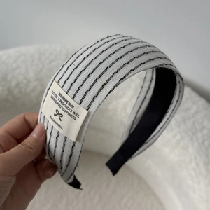 Detailed macro view of woven black and white striped headband with sewn brand fabric label