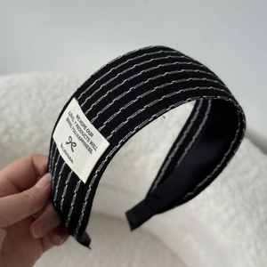 Detailed macro view of black striped headband fabric with white embroidered lines and woven tag