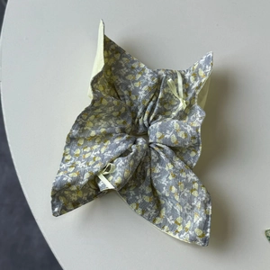 Detail of floral hair scrunchie with grey fabric and yellow bow accents for women