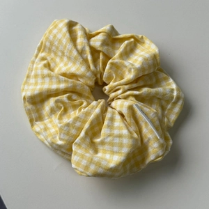 Detail of yellow plaid scrunchie with handmade tag showing textured cotton fabric