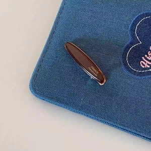Détail d'une barrette à cheveux en acétate ambré fait main sur un tissu en jean bleu