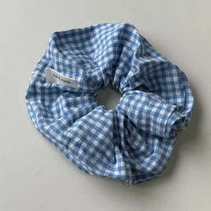 Detail of blue and white plaid fabric scrunchie with handmade label and pleated texture