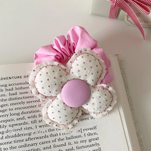 Gedetailleerde close-up van roze polkadot stoffen bloem haarelastiekje op oude boekpagina's