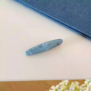 Détail d'une pince à cheveux en acétate bleu marbré avec lettrage doré Paris chic