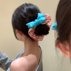 Blue bow scrunchie with red white stripes shown on a messy bun hairstyle
