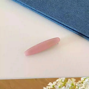 Gros plan détaillé d'une pince à cheveux en acétate rose avec finition lisse et clip argenté