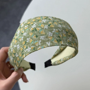 Close-up of green floral headband featuring yellow flowers and vertical ribbed texture