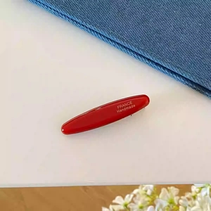 Détail de la pince à cheveux rouge en acétate avec inscription dorée France Handmade gravée